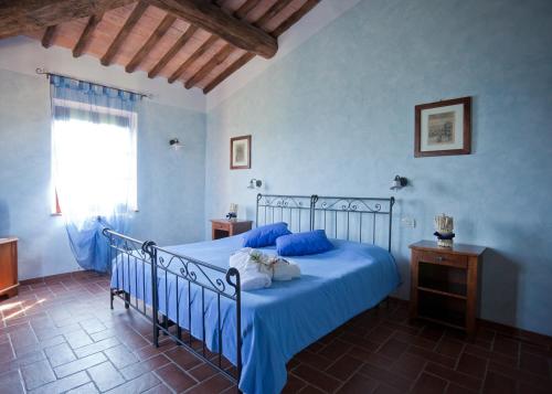 a bedroom with a bed with blue sheets and a window at Fattoria Fibbiano in Terricciola