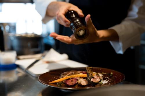 a person holding a bottle of wine next to a plate of food at WEAZER 西伊豆 in Izu