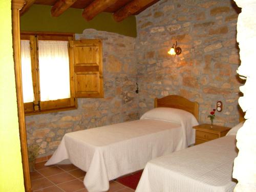 a bedroom with two beds and a stone wall at Casa Rural el Castellet in La Jana