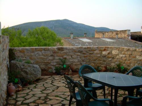 patio ze stołem i krzesłami oraz kamienną ścianą w obiekcie Casa Rural el Castellet w mieście La Jana
