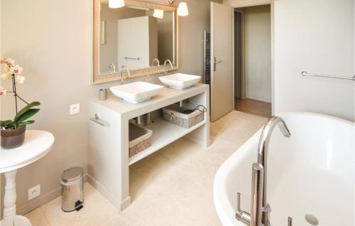 een badkamer met 2 wastafels, een bad en een spiegel bij Cozy Home In St, Gilles With Outdoor Swimming Pool in Beauvoisin