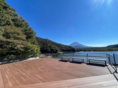 two benches sitting on a deck overlooking a body of water at Shoji Lake Hotel in Fujikawaguchiko