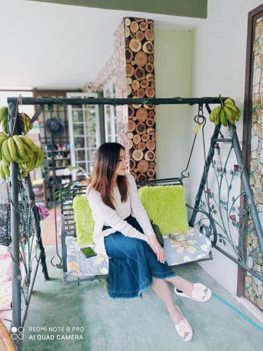a woman sitting on a chair on a porch at Bdr Bukit Tinggi Klang Tropicana Garden Homestay in Klang