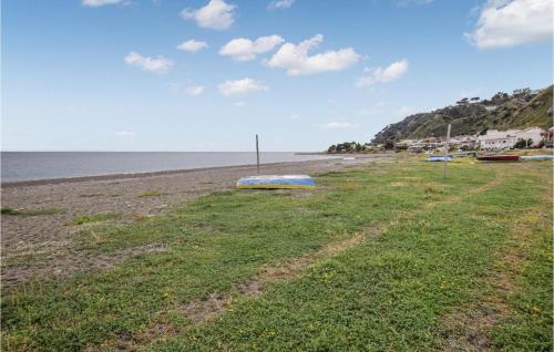 a beach with a blue boat sitting on the grass at 2 Bedroom Awesome Apartment In Messina in Briga Marina
