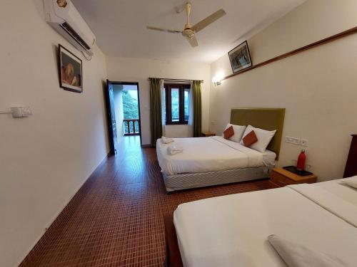 a hotel room with two beds and a balcony at THE TIGER PAW RESORT in Masinagudi