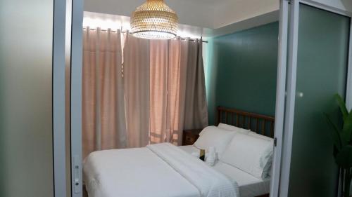 een slaapkamer met een wit bed en een kroonluchter bij Relaxing 1BR Sanctuary at Azure with Wi-Fi in Manilla