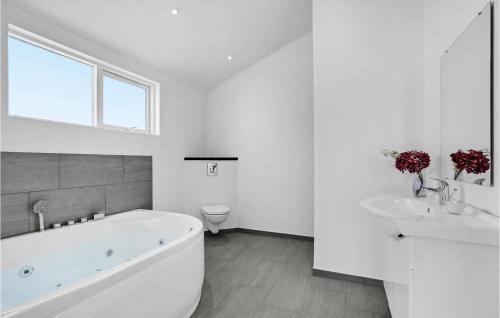 Baño blanco con bañera y lavamanos en Amazing Home In Lkken With Wifi, en Løkken