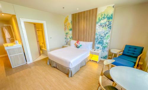 a bedroom with a bed and a blue chair at Harolds Hotel Quezon City in Manila