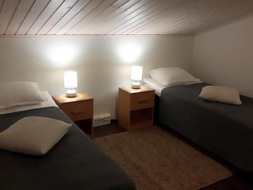 two beds in a room with two lamps on night stands at Apartment Marta in Vuokatti