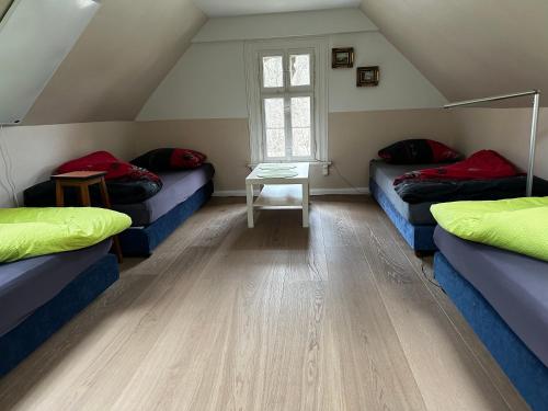 a attic room with three beds and a table at Bahnhof Paulinzella mit Sauna in Königsee