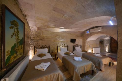 a room with four beds in a stone room at Emit Sakura Cave Hotel in Göreme