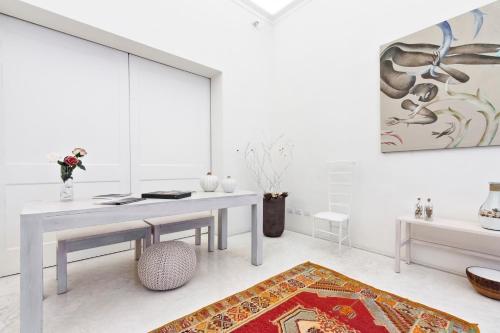 a white living room with a table and a rug at Casa di Lo Suites in Lecce