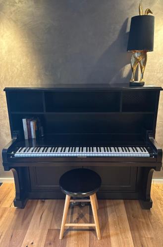 a black piano with a lamp and a stool at Designapartment 2.0 in Lutherstadt Wittenberg