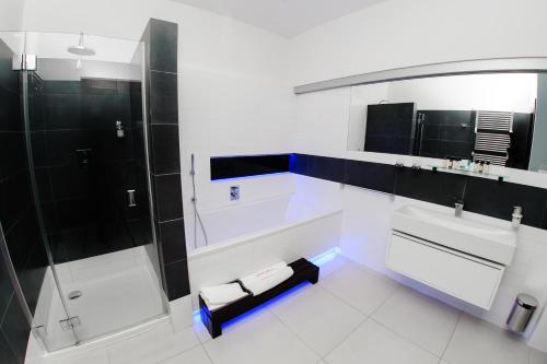 a white bathroom with a shower and a bench at Hotel Magnus Trenčín in Trenčín