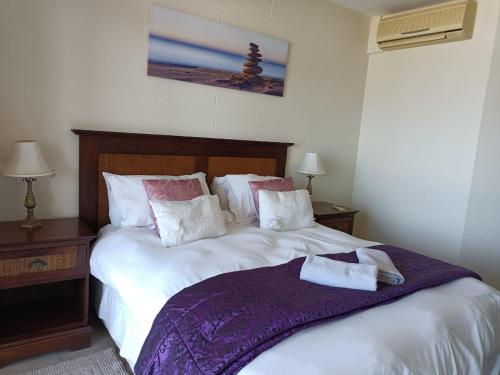 a bedroom with a large bed with a purple blanket at Santorini 206B -Margate RSA in Margate