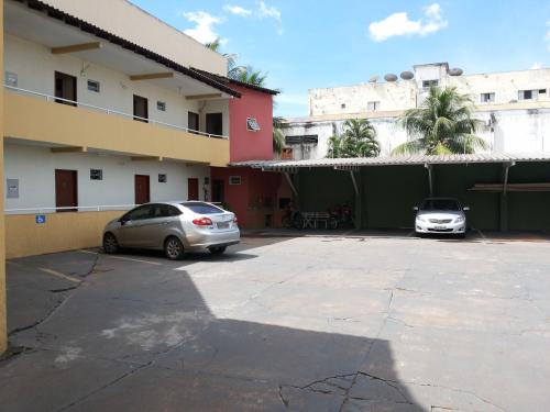 two cars parked in a parking lot next to a building at Hotel Casa Nova in Várzea Grande