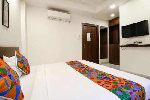 a bedroom with a bed and a tv on the wall at FabExpress Comfort Stay I in Bhopal