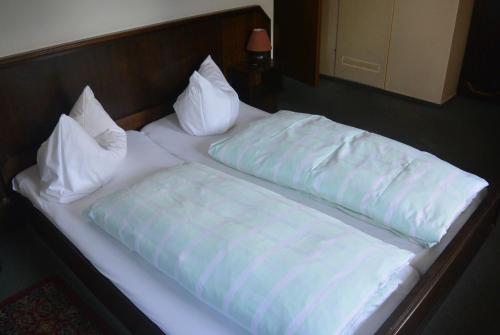 ein Bett mit weißer Bettwäsche und Kissen darauf in der Unterkunft Naumann`s Hotel & Restaurant in Burgstaedt