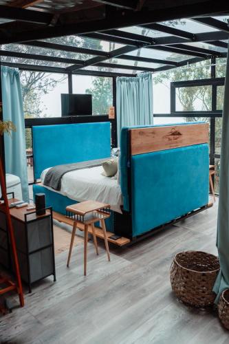 a bedroom with a blue bed and a chair at The Stargazing Cube - Misty Mountain Reserve in Stormsrivier