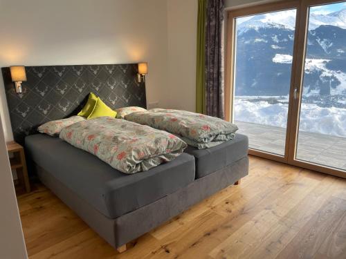 um quarto com uma cama e uma grande janela em Ferienwohnung Traumblick -Familie Seber em Mittersill
