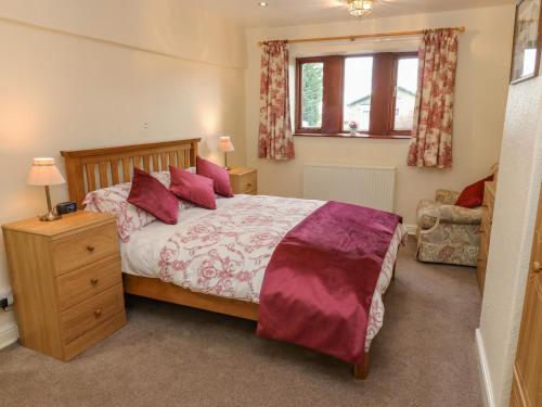 a bedroom with a large bed with red pillows at Butts Cottage in Farnley Tyas