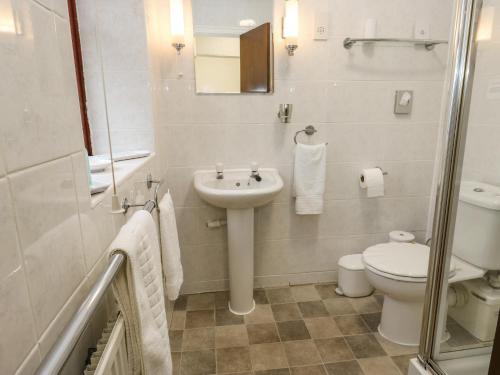 a white bathroom with a sink and a toilet at Butts Cottage in Farnley Tyas