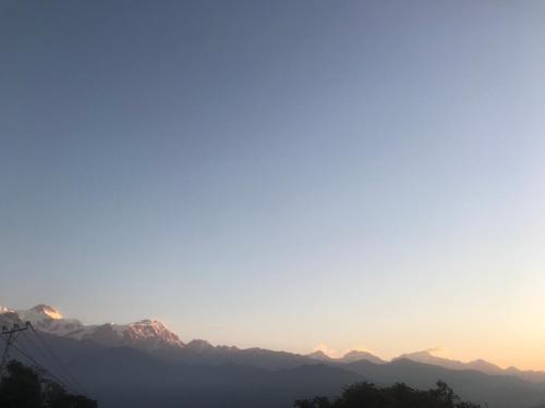 a view of a mountain range with the sun setting at Hilltop Restaurant and guesthouse in Pokhara