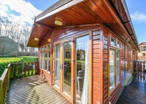 a wooden house with glass doors on a deck at South Lakeland Leisure Village in Hornby