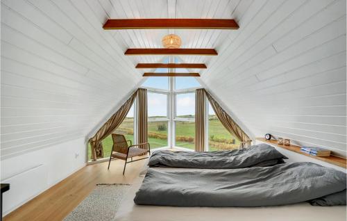 SkattebølleにあるNice Home In Tranekr With House Sea Viewの屋根裏のベッドルーム(ベッド2台、椅子付)