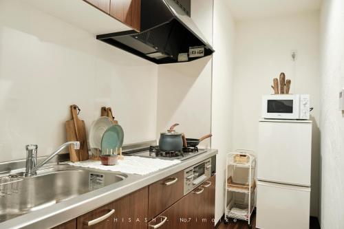 a small kitchen with a sink and a microwave at 久HISASHI 今池 Nagoya in Nagoya