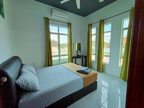 a bedroom with a large bed with yellow curtains at Aja Retreat Chalet in Jitra