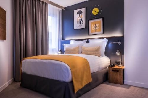 a bedroom with a large bed with blue walls at Best Western Plus Suitcase Paris La Défense in Bois-Colombes