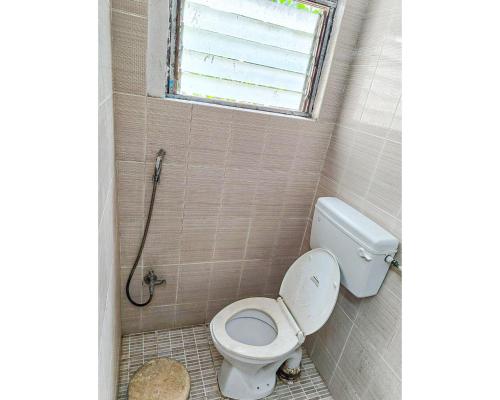a bathroom with a toilet and a window at Devi Deluxe Lodge By WB Inn in Secunderabad