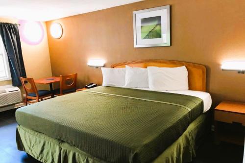 タラハシーにあるOYO Hotel Tallahassee Downtownの大きなベッドとテーブルが備わるホテルルームです。