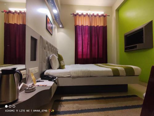 a bedroom with a bed and a desk and a tv at Hotel Prabhat in Varanasi