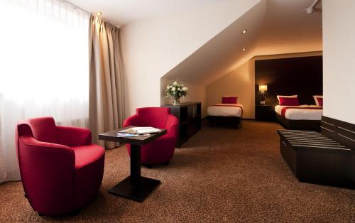 a hotel room with two beds and red chairs at Van der Valk Hotel Avifauna in Alphen aan den Rijn