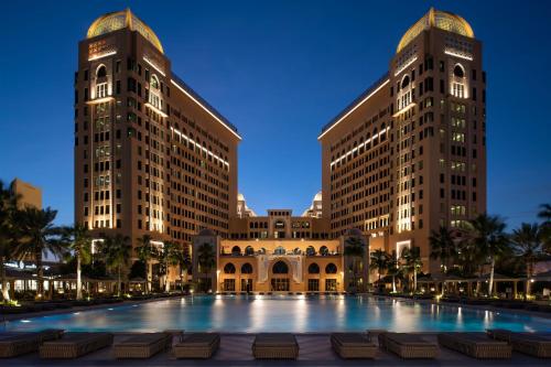a building with a large pool in front of two tall buildings at The St. Regis Doha in Doha