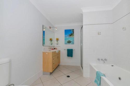 ein weißes Badezimmer mit einer Badewanne und einem Waschbecken in der Unterkunft Breakwater 16 in Townsville