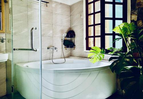 uma casa de banho com uma banheira e um chuveiro em vidro. em The First Ba Trieu Ha Noi em Hanói