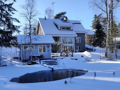a house in the snow with a pond in front at Room by Lake 10 minutes from Tampere centrum in Lempäälä