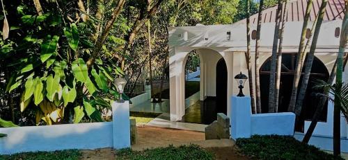 a house with a white arch and a building at Ovitiyas Bandarawela in Bandarawela