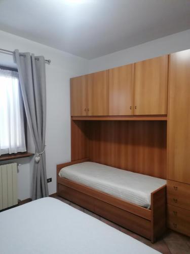 a bedroom with a bed and wooden cabinets at Sweet Home Casa Vacanze "Il Bilocale" in Songavazzo