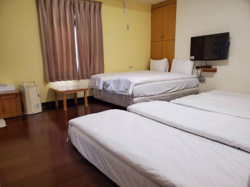 a hotel room with three beds and a flat screen tv at Youran B&B in Jiufen