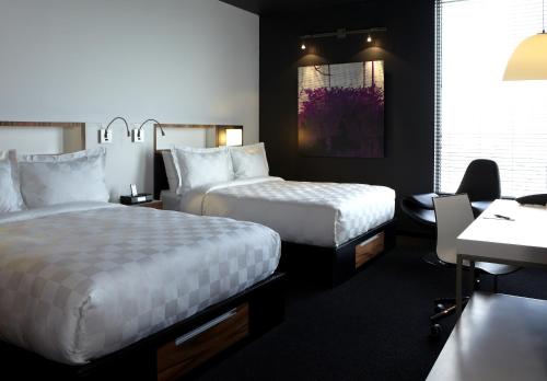 a hotel room with two beds and a desk at Alt Hotel Toronto Airport in Mississauga