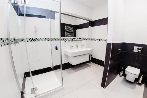 a white bathroom with a sink and a shower at Hotel Magnus Trenčín in Trenčín