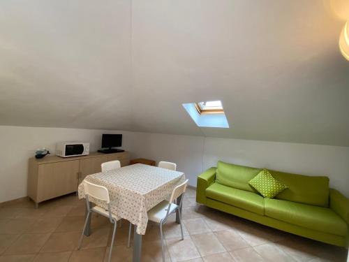 een woonkamer met een tafel en een groene bank bij Luci in San Vincenzo
