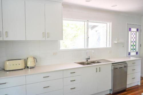 a kitchen with white cabinets and a sink and a window at The Beach House in Pallarenda