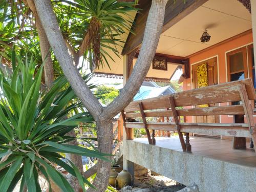 a porch of a house with a bench and trees at Sawasdee Sichang Resort in Ban Tha Thewawong