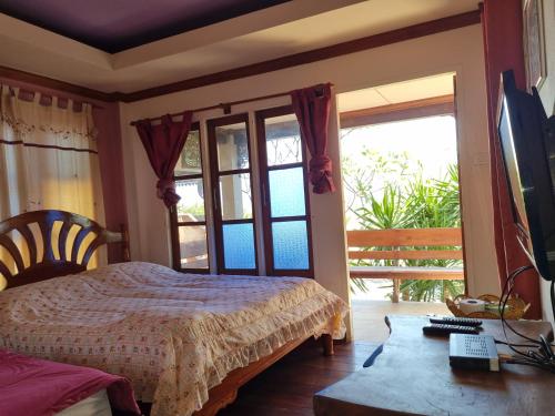1 dormitorio con 1 cama, TV y ventana en Sawasdee Sichang Resort en Ban Tha Thewawong