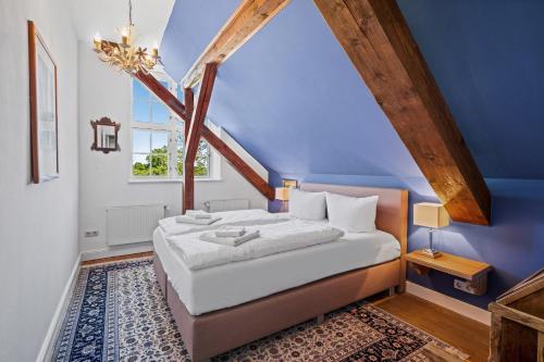 a bedroom with a bed with a blue wall at GUT KLETKAMP "Storchennest" - Ferienwohnung im Schlossturm mit 3 Schlafzimmern I Panorama-Turmzimmer mit Naturblick I Gemeinschaftsgarten I 15 Min zur Ostsee I Küche I Parkplatz I WLAN in Kletkamp